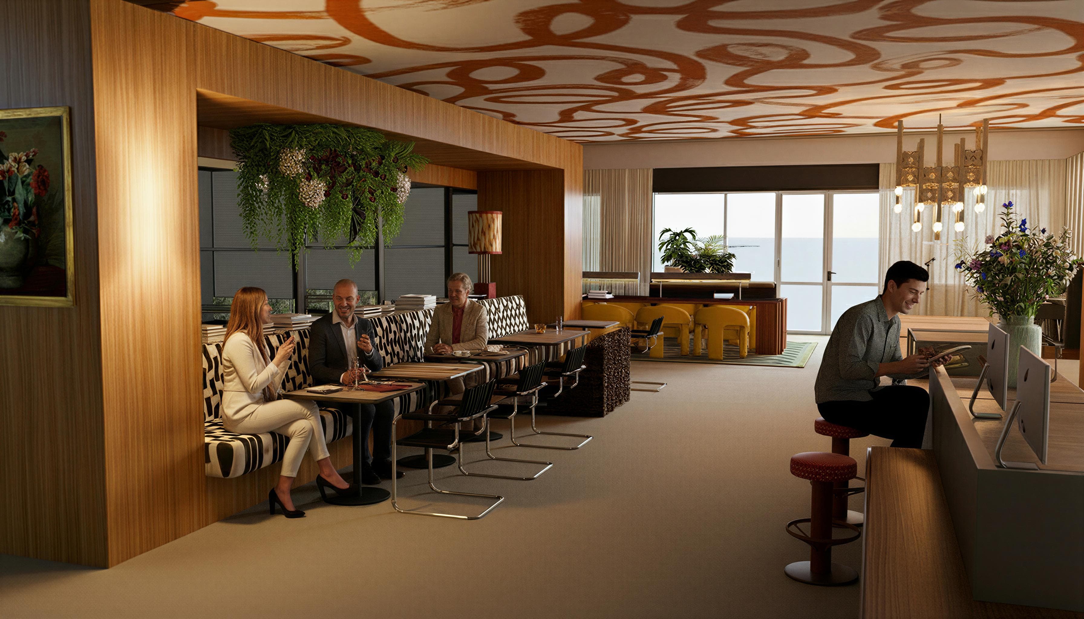 A modern lounge with people seated on patterned chairs, a man using a laptop at a counter, and large windows showing an ocean view.