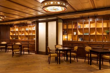 Cozy, dimly lit room with wooden floors, vintage furniture, and a stained glass ceiling light, creating a warm, inviting atmosphere.